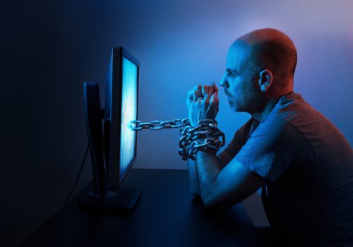 A man is chained to computer late at night.